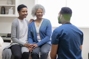 A woman shows how to advocate for your older loved ones by sitting with her elderly mother at the doctor’s office and communicating with the doctor.