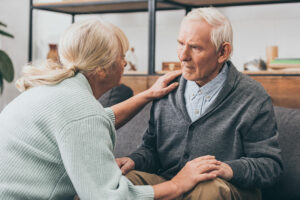 A woman leans forward with concern in response to noticing chronic negativity in an older loved one.