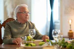 A man sits alone at the dinner table, representing the need for socialization for introverted seniors.