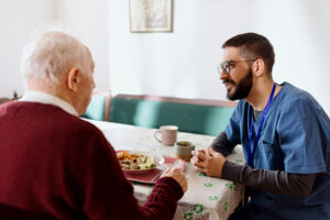 A young man sits with his father to share mealtime together, one of the ways to help if you’re noticing changes in a senior’s eating behaviors.