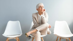 A woman who has learned how to become a more patient caregiver relaxes in a waiting room with a serene expression on her face.