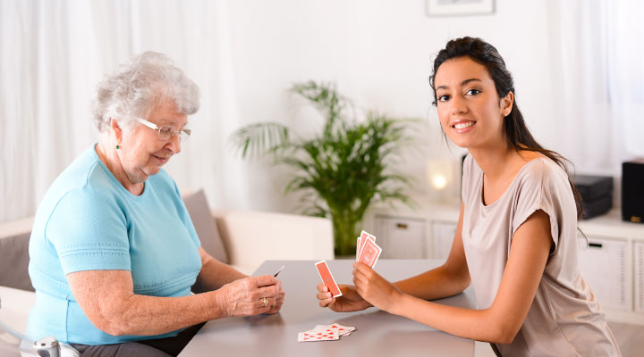 An older woman receiving companion care services near Novato plays a card game with her caregiver.