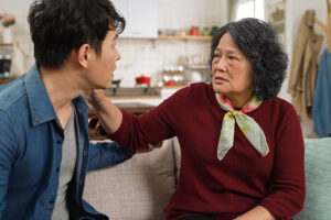 An older woman experiencing loss of recognition in dementia looks confused as she talks with her son.