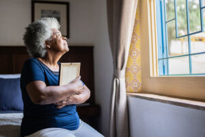 A woman grieving after the death of a loved one holds a picture in her arms.