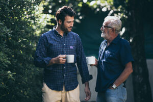 An older man talks with his son as they take a walk together, one great way to prevent senior social frailty.