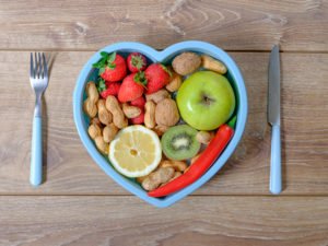 Heart shaped dish with vegetables isolated on wooden background