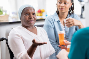 Aging patient discusses medication with nurse