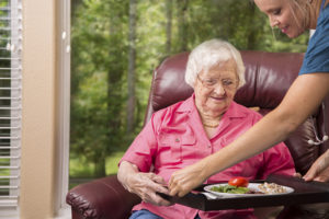 happy-caregiver-serving-senior-woman